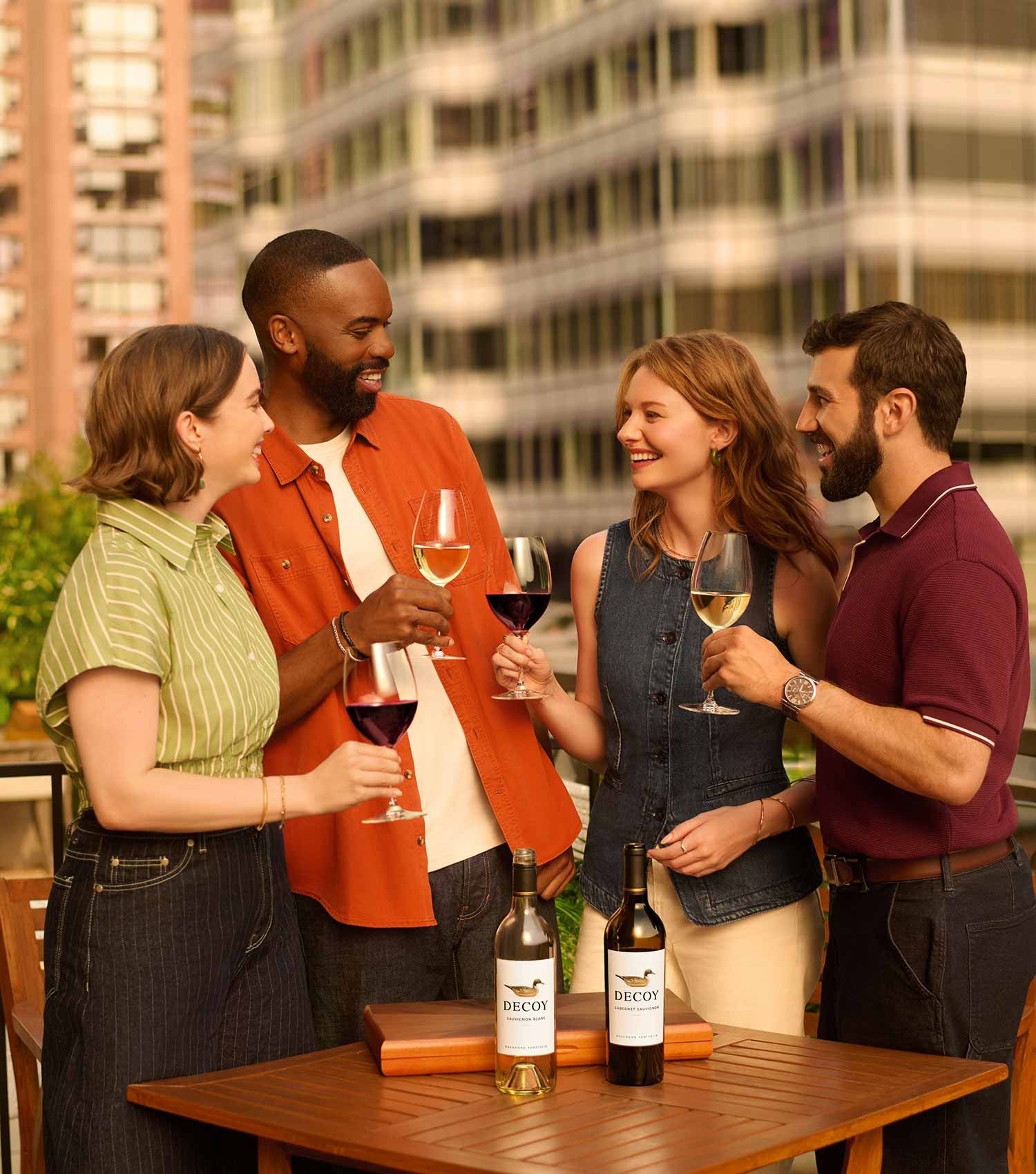 Four people enjoying wine on a rooftop with cityscape in the background